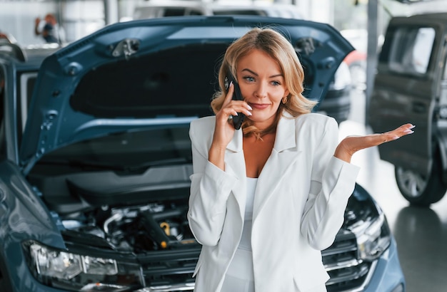 Foto falando por telefone mulher em roupas formais está dentro de casa no salão automático