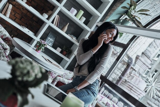 Foto falando sobre negócios. mulher jovem e atraente sorridente falando no telefone inteligente