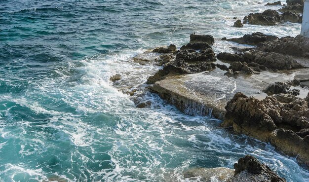 falésia junto ao mar Mediterrâneo, ondas fortes quebram com as rochas e deixam cores azul e turquesa junto com a espuma do mar.