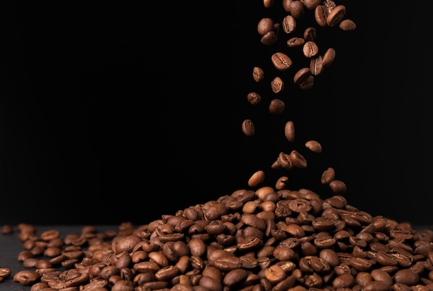 Foto fallende braune kaffeebohnen auf schwarzem hintergrund herunterfliegen