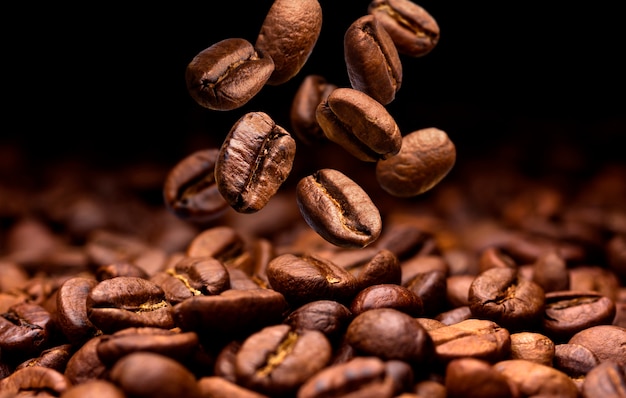 Fallende Kaffeebohnen. Dunkler Hintergrund mit Kopienraum