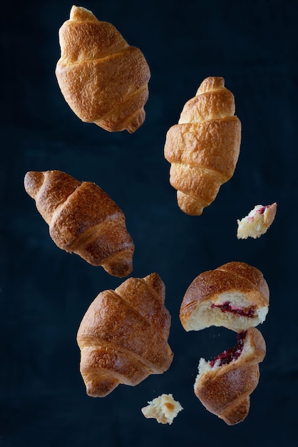 Fallende köstliche frisch gebackene Croissants auf blauem Hintergrund