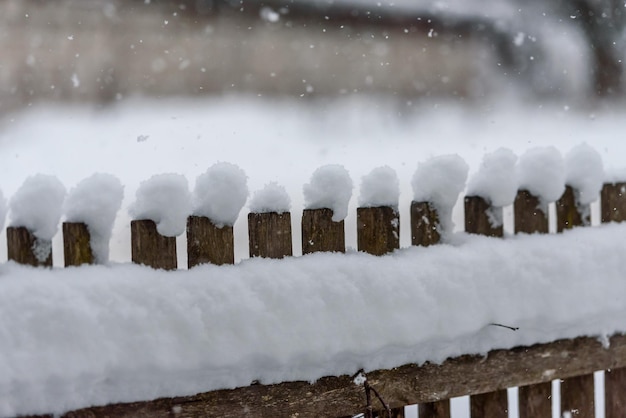 Fallender Schnee auf dem Hintergrund eines alten Bretterzauns eine rustikale Winterlandschaft
