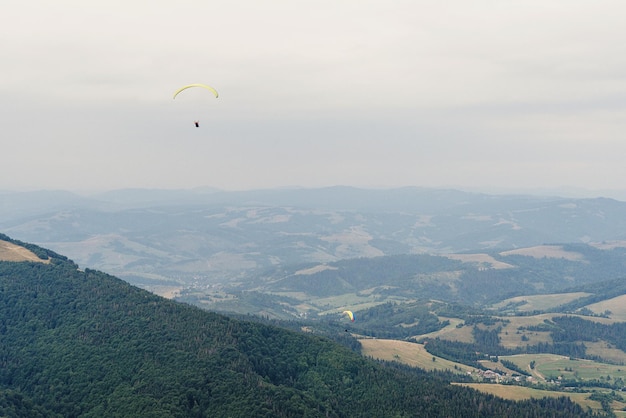 Fallschirmspringer, der in Wolken auf der Spitze der Berge fliegt, mit fantastischem Blick auf das Reiseabenteuerkonzept, Platz für Text