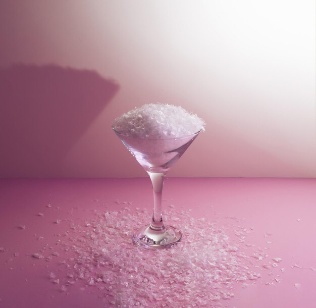 Falscher Schnee in Martini-Cocktailgläsern auf rosa Hintergrund Winter kreative Idee ästhetische Weihnachten