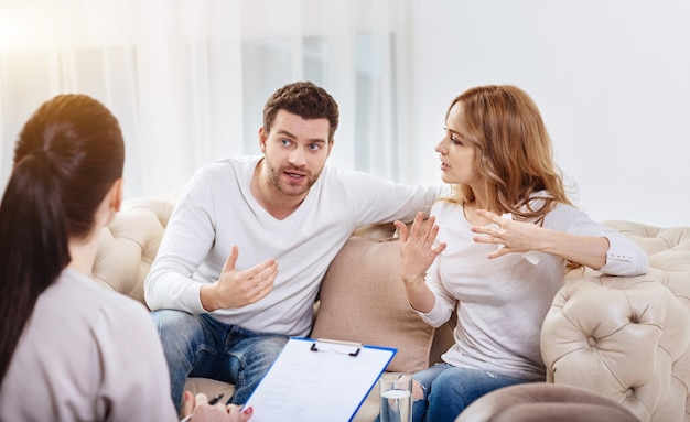 Falta de comunicação entre as pessoas. Jovem e mulher desanimados, sentados no sofá e gesticulando enquanto discordam