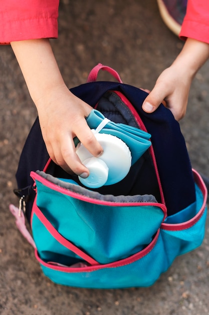 Foto faltbare silikonflasche in der hand eines kleinen mädchens, das sie in den rucksack steckt