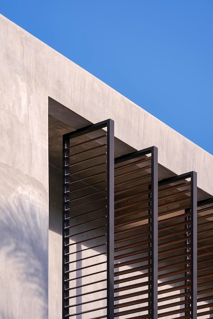 Faltbare Sonnenschutzlatten aus Metall an der Betonwand des Hausbaus im Loft-Stil gegen den blauen Himmel