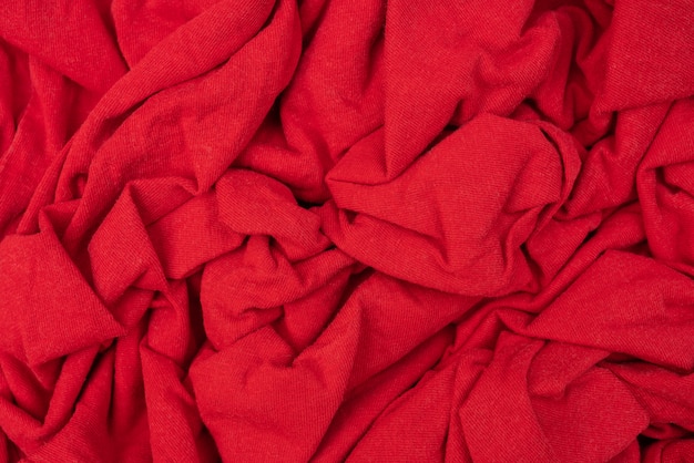 Falten aus zerknitterter Wolle. Textilprodukt. Abstrakter roter Hintergrund.