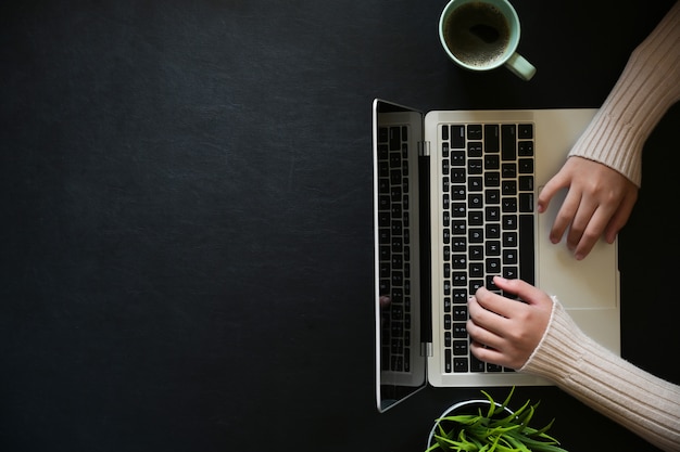 Famale, der mit Laptop auf dem dunklen ledernen Bürodesktop und Kopienraum arbeitet