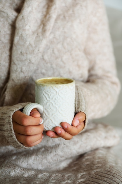 Famale mãos segurando uma caneca artesanal cerâmica aconchegante com café. Conceito de tempo para casa de inverno e Natal. Estilo de vida.