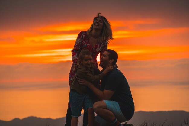 Foto familia abrazándose en la cima de una montaña al atardecer