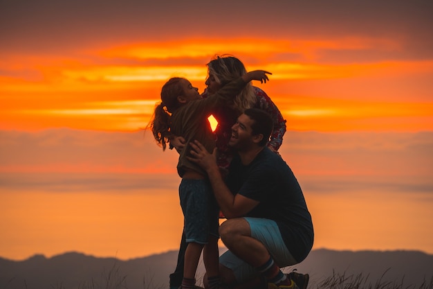 Familia abrazándose en la cima de una montaña al atardecer