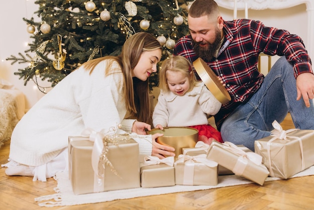 Família abrindo presentes de Natal perto de árvore decorada