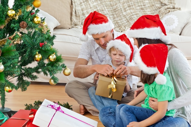 Família abrindo presentes de natal sentado no chão