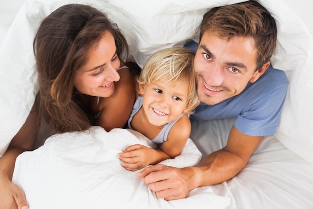 Familia acostada en el edredón en la cama