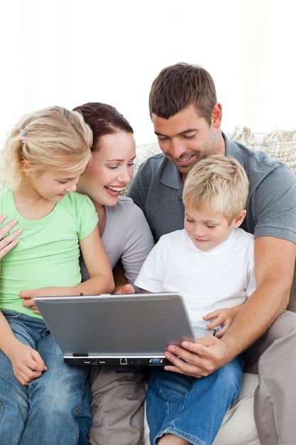 Família adorável trabalhando juntos em um laptop sentado no sofá