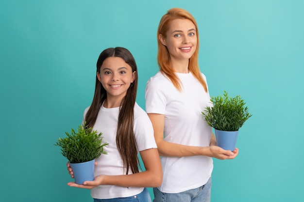 Família adotiva de filha adotiva e mãe mulher sorriem segurando vasos de plantas, adotivos