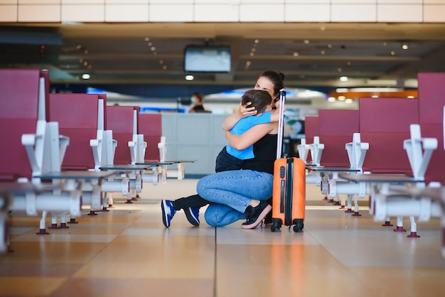 Familia en el aeropuerto antes del vuelo. Madre e hijo esperando para embarcar en la puerta de salida de la moderna terminal internacional. Viajar y volar con niños. Mamá con avión de embarque para bebés y niños pequeños.