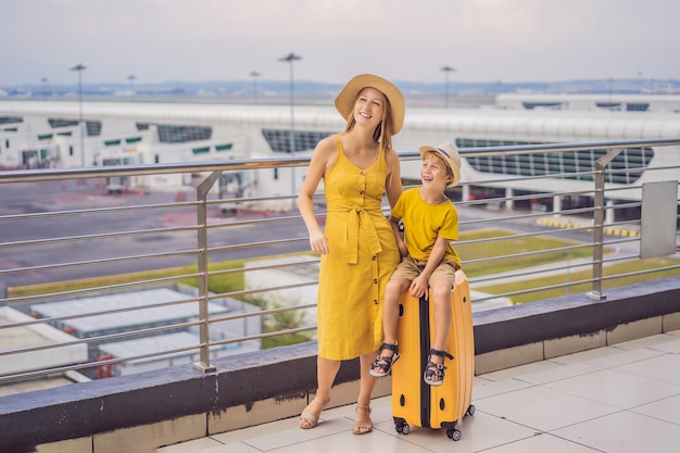 Foto familia en el aeropuerto antes del vuelo madre e hijo esperando para embarcar en la puerta de salida de la moderna terminal internacional viajar y volar con niños mamá con niño abordando el avión amarillo aspecto familiar