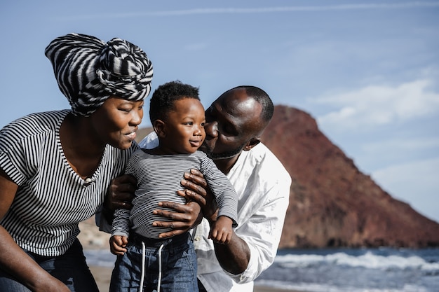 Família africana brincando na praia nas férias de verão - Foco no rosto da mãe - Foco principal no rosto da criança