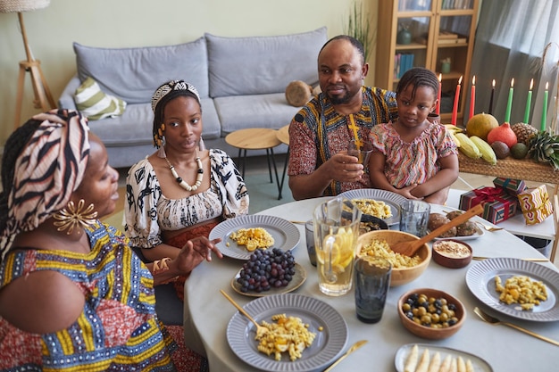 Família africana de quatro jantando à mesa em casa celebrando kwanzaa junto com