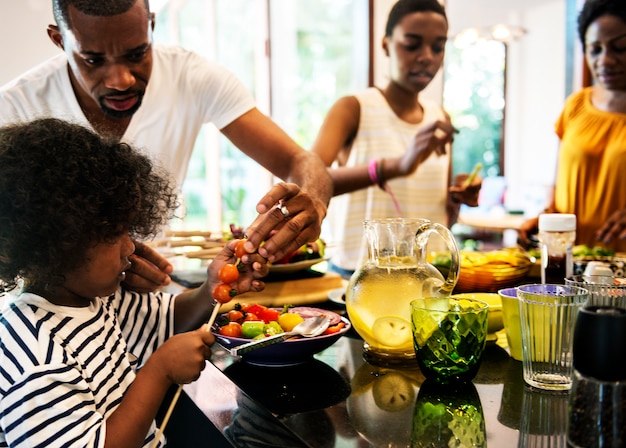 Familia africana preparando barbacoa en la cocina juntos