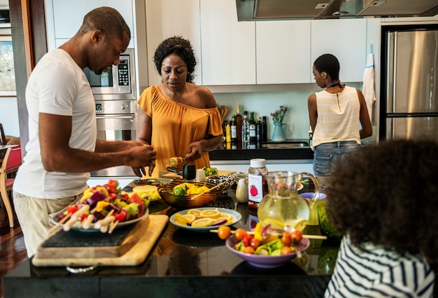 Família africana preparando churrasco na cozinha juntos