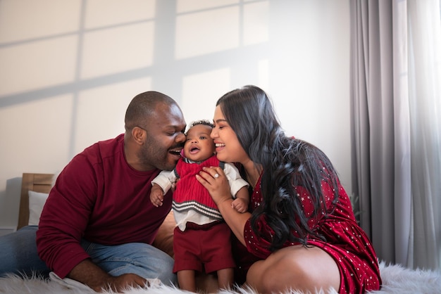 Familia africana sosteniendo y besando a un bebé recién nacido de 4 meses sonríen y felices juntos.