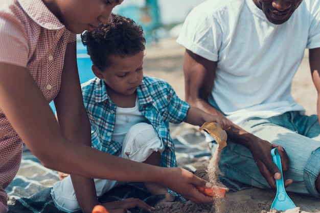 Família afro-americana está descansando na praia