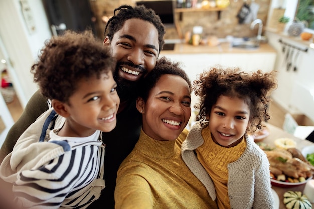 Foto família afro-americana feliz tomando selfie durante o almoço de ação de graças na sala de jantar