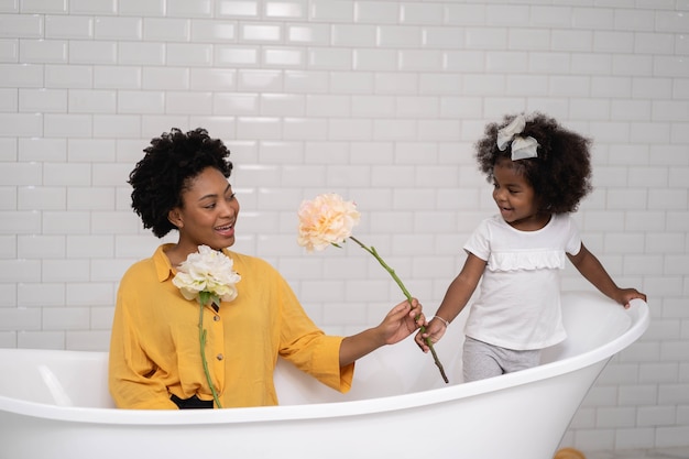 Família afro-americana, mãe feliz e filha se divertindo e brincando juntas no banheiro