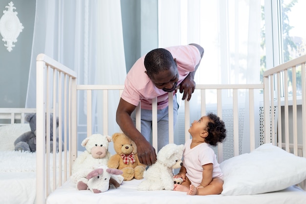 Família afro-americana, pai e filho conversando ou brincando no quarto em casa, pai feliz