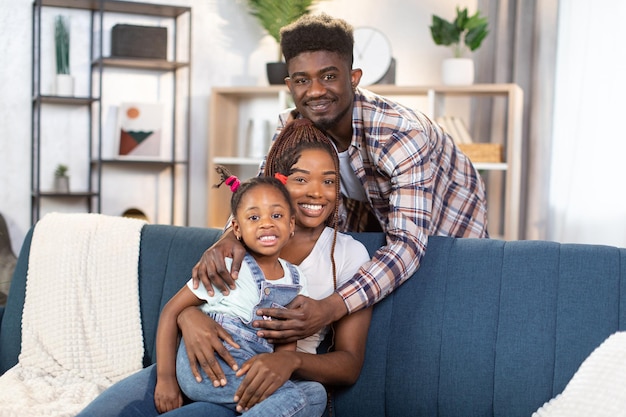 Família afro-americana posando no sofá confortável em casa