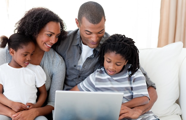 Família afro-americana usando um laptop no sofá