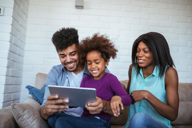 Familia afroamericana feliz navegando por la red en la tableta