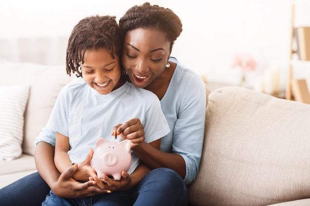 Familia afroamericana insertando dinero en la alcancía
