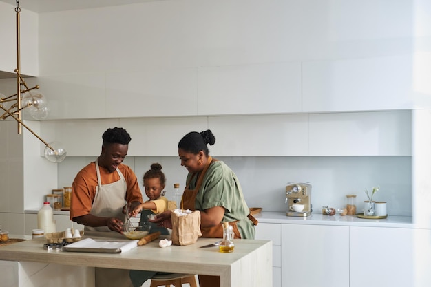 Familia afroamericana de tres horneando juntos en la cocina moderna