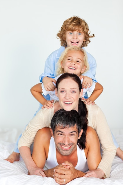 Familia alegre acostada en una cama blanca