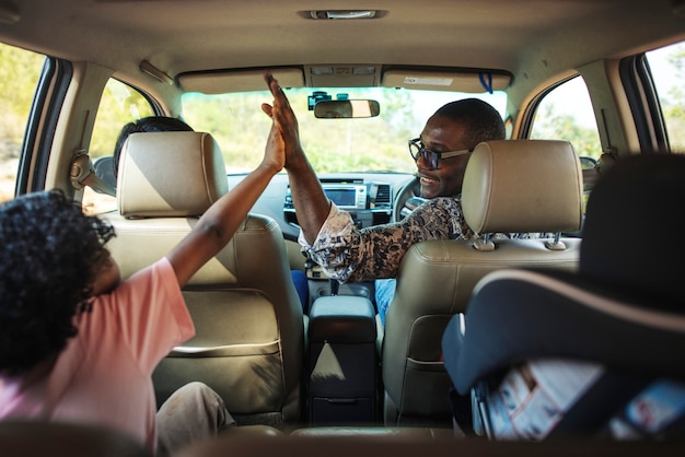 Familia alegre en un coche en un viaje por carretera