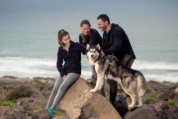 Família alegre com Husky na costa