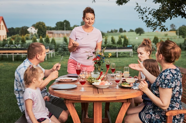 Família alegre comendo comida sentada ao ar livre