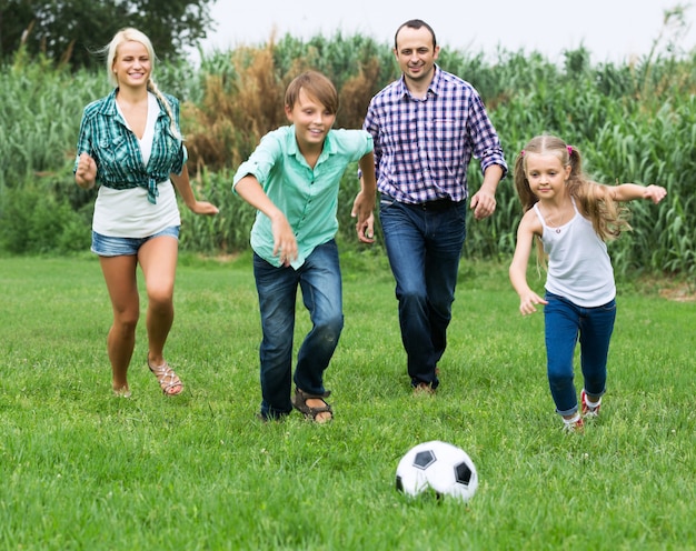 Foto família alegre correndo com bola
