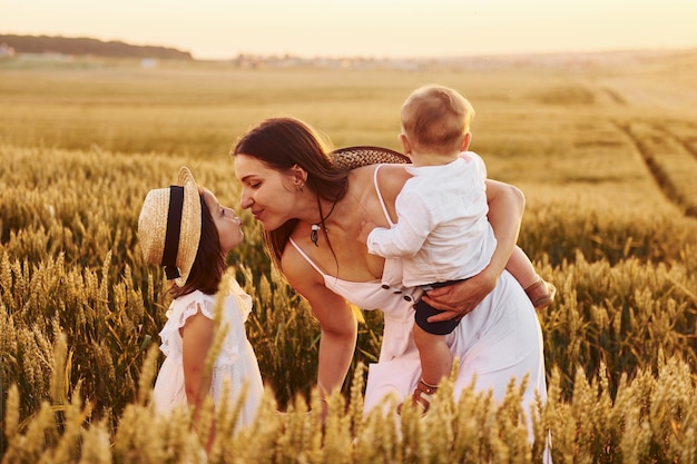 Família alegre de mãe filho e filha passando tempo livre no campo na hora do dia ensolarado de verão