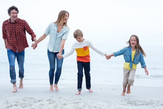 Família alegre, de mãos dadas enquanto caminhava na beira-mar