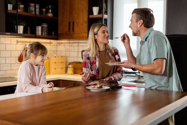 Família alegre desfrutando de bolo de chocolate caseiro em uma cozinha aconchegante