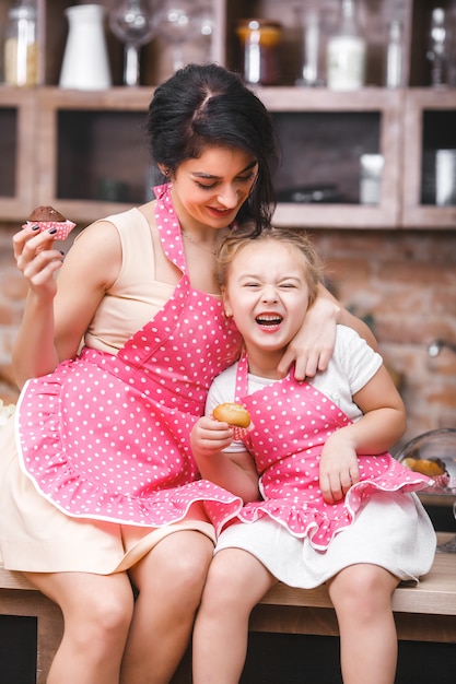 Familia alegre divirtiéndose en la cocina. Joven madre y su pequeña hija horneando juntas