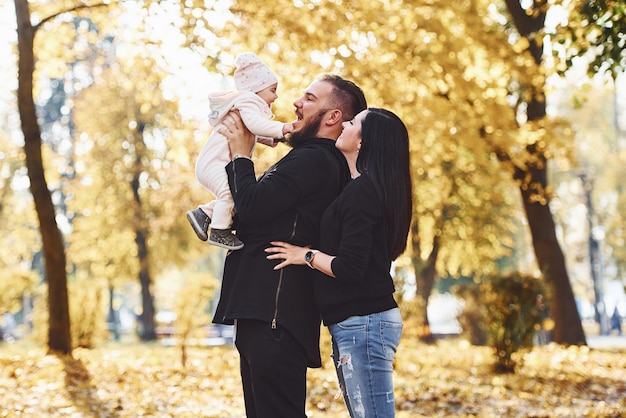 Familia alegre divirtiéndose junto con su hijo en el hermoso parque de otoño.