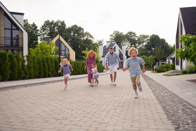 Familia alegre encantada corriendo en la calle