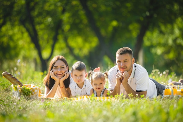 Família alegre fazendo piquenique. Pais jantando com os filhos ao ar livre.